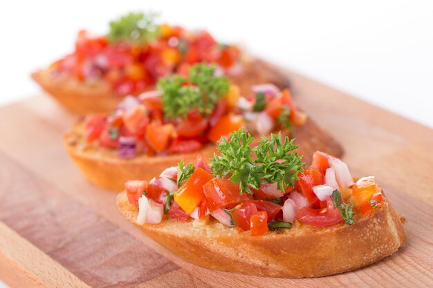 Bruschetta italiana con tomates asados, queso mozzarella y hierbas sobre una tabla para cortar