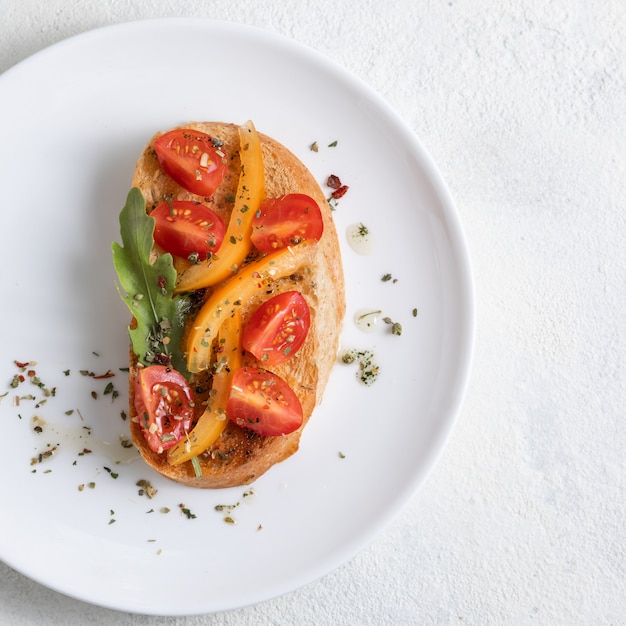 Bruschetta italiana con tomates en un plato blanco sobre fondo blanco. Vista desde arriba