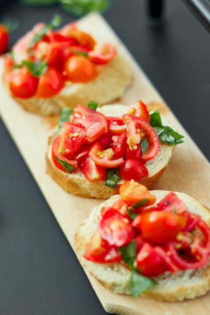 Bruschetta italiana con tomates rojos frescos y hierbas de albahaca en una tabla de madera al aire libre