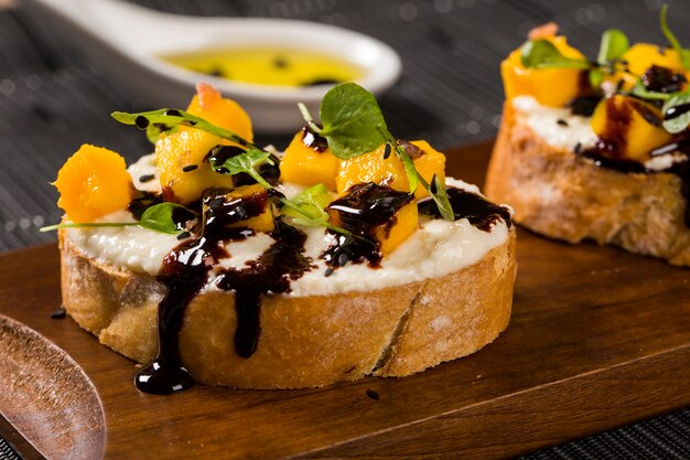 Bruschetta con mango picado, berro, albahaca y queso de cabra en baguette fresco sobre la mesa