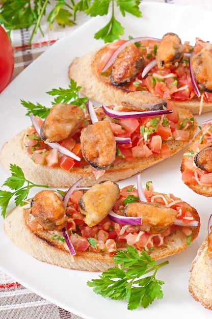 Bruschetta con mejillones, queso y tomates.