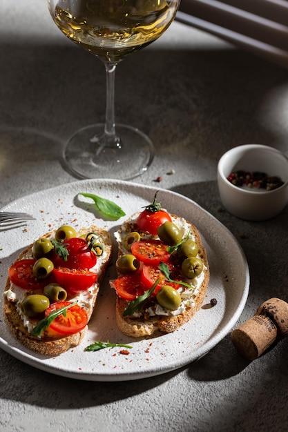 Bruschetta mit frischen Tomaten und Oliven auf einem Teller und einem Weinglas