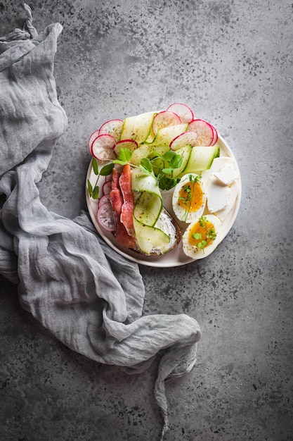 Bruschetta mit Gurke und Lachs mit Eiern und Mikrogrün auf grauem Betongrund