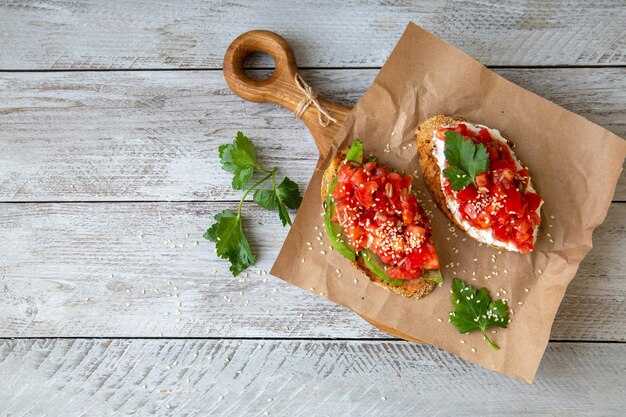 Bruschetta mit Hüttenkäse, Avocado, Tomaten, Grüns, weißem Sesam, Gesundes Essen, reich an gesunden Fetten, Ballaststoffen, Vitaminen, Antioxidantien. Vegetarisches Essen