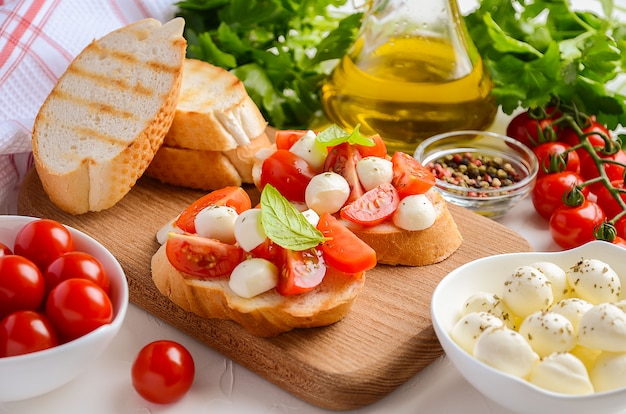 Bruschetta mit Kirschtomaten und Mozzarella auf hölzernem Schneidebrett.