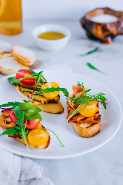 Bruschetta mit Kirschtomatensalat mit gegrilltem Haloumi-Käse, mit Mangoldgemüse und Arugula