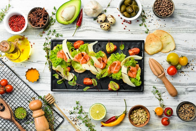 Bruschetta mit Lachssalat und Parmesankäse auf einem schwarzen Teller Draufsicht Rustikaler Stil