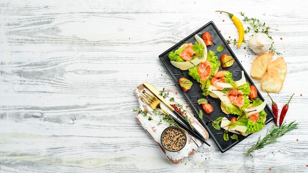 Bruschetta mit Lachssalat und Parmesankäse auf einem schwarzen Teller Draufsicht Rustikaler Stil