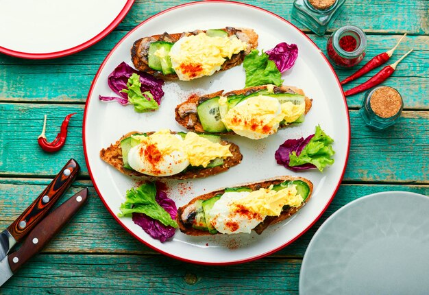 Bruschetta mit pochiertem Ei, Gurke und gebratenen Champignons mit Sauce Hollandaise. Leckere Eier Benedict