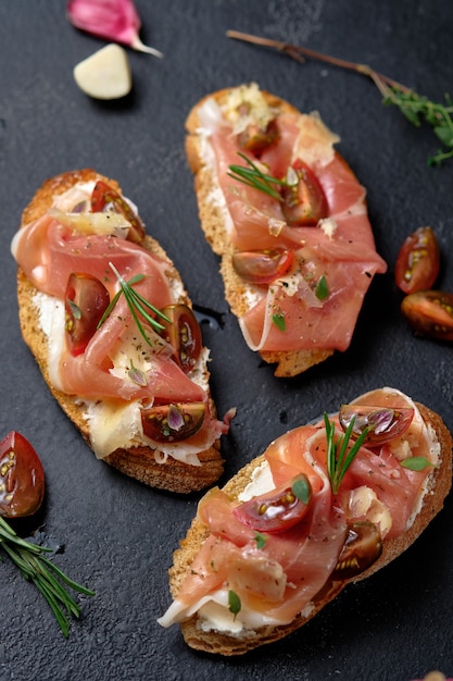 Bruschetta mit Prosciutto Hartkäse Tomaten Kräutern und Gewürzen auf einem Holzbrett