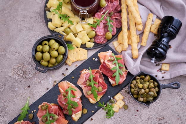 Bruschetta mit Prosciutto-Schinken und Kapern mit traditioneller Antipasti-Fleischplatte im Hintergrund