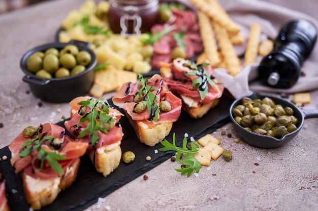 Bruschetta mit Prosciutto-Schinken und Kapern mit traditioneller Antipasti-Fleischplatte im Hintergrund