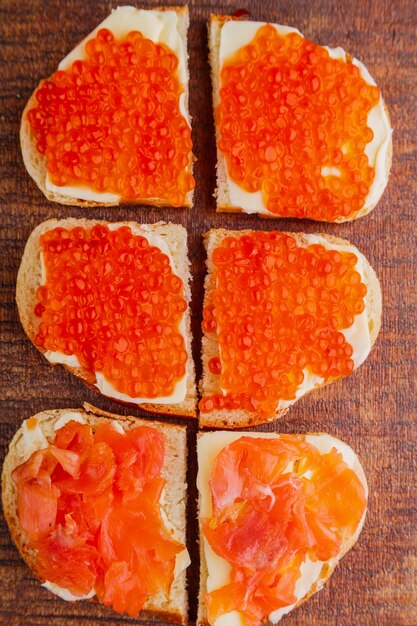 Bruschetta mit rotem Kaviar und Fisch auf einem Holzbrett.