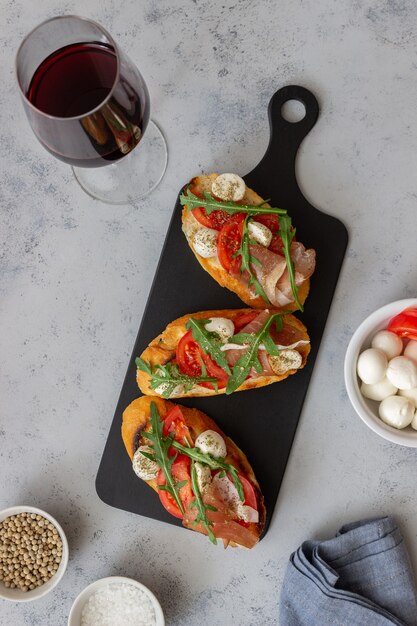 Bruschetta mit Schinken, Mozzarella, Tomaten und Rucola. Wein Vorspeise. Snack.