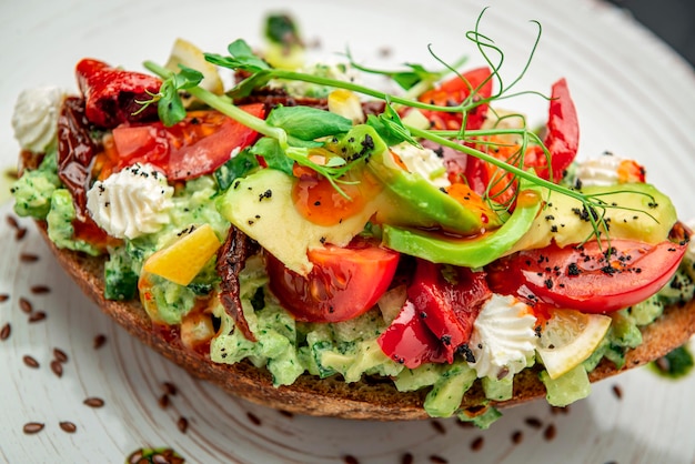 Foto bruschetta mit sonnengetrockneten tomaten, frischkäse, avocado und frischem gemüse