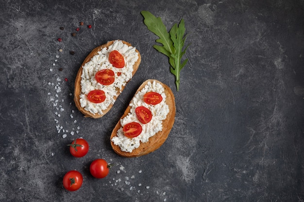 Bruschetta mit Tomaten und Käse auf einem dunklen Hintergrund mit Grüns. Draufsicht, Kopie, Raum.