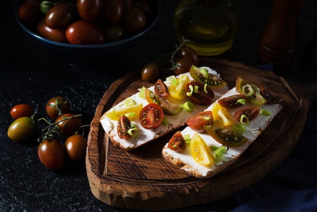 Bruschetta mit Tomaten und Olivenöl auf einem Holzbrett - traditioneller italienischer, spanischer Snack, selektiver Fokus