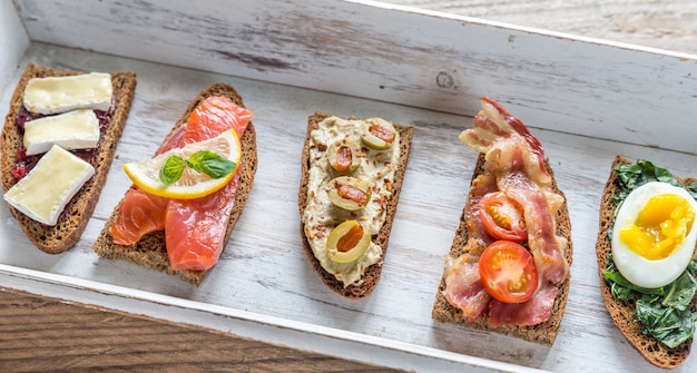 Bruschetta mit verschiedenen Belägen auf einem Holztablett