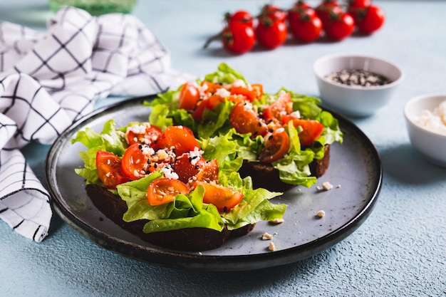 Bruschetta en pan de centeno con tomates de lechuga y sésamo en un plato en la mesa