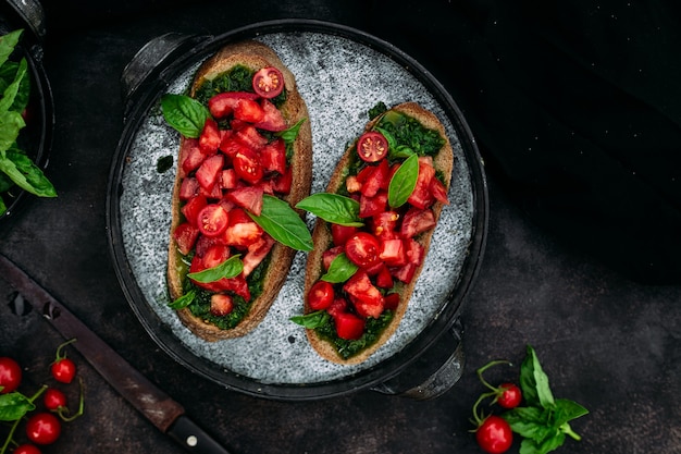 Bruschetta con pesto y tomates sobre un fondo oscuro