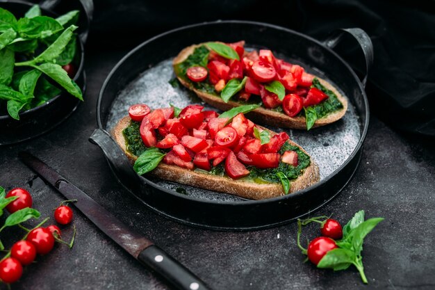 Bruschetta con pesto y tomates sobre un fondo oscuro