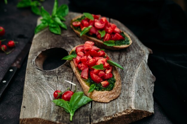 Bruschetta con pesto y tomates sobre un fondo oscuro