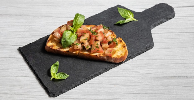 Bruschetta Un plato de tostadas con una rodaja de tomate y albahaca.