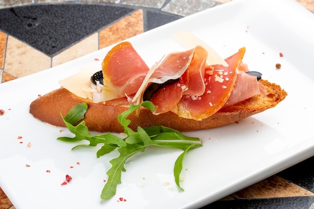 Bruschetta con prosciutto y rúcula en un plato blanco