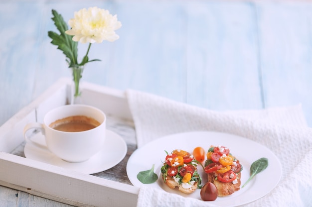 Bruschetta con queso, albahaca, rúcula y tomates cherry y una copa de vino blanco