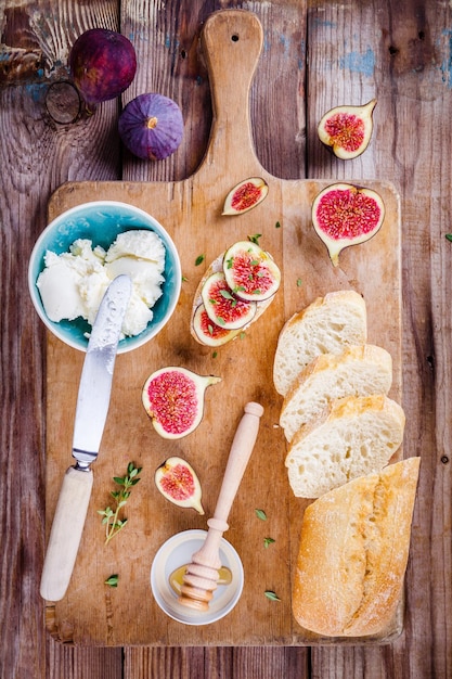 Bruschetta con queso de cabra, higos frescos, miel y tomillo sobre tabla de madera