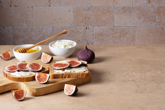 Bruschetta con queso crema de higos y miel se encuentra en una tabla de cortar de madera