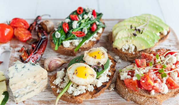 Bruschetta saboroso e delicioso com tomate, espinafre, feta abacate pimenta vermelha e queijo azul.