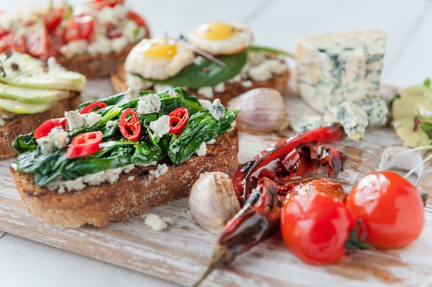 Bruschetta saboroso e delicioso com tomate, espinafre, feta abacate pimenta vermelha e queijo azul.