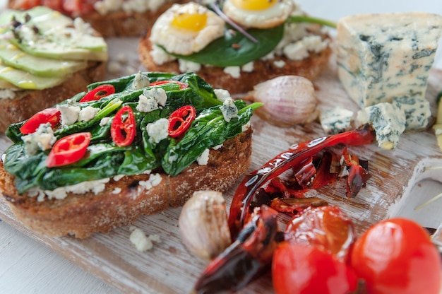 Bruschetta saboroso e delicioso com tomate, espinafre, feta abacate pimenta vermelha e queijo azul.