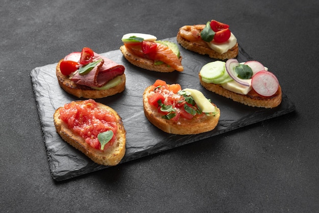 Bruschetta-Set vor dunklem Hintergrund italienische Vorspeise auf Schiefer