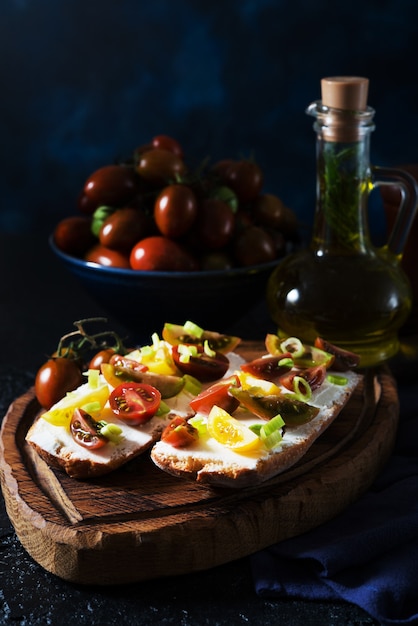 Bruschetta con tomate y aceite de oliva sobre una tabla de madera - aperitivo tradicional italiano, español, enfoque selectivo