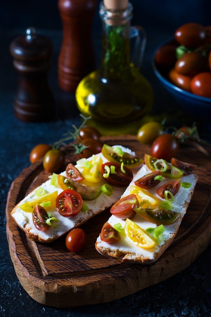 Bruschetta con tomate y aceite de oliva sobre una tabla de madera - aperitivo tradicional italiano, español, enfoque selectivo