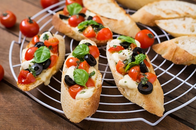 Foto bruschetta con tomate, mozzarella, aceitunas y pesto de albahaca