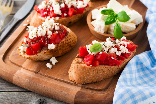 Bruschetta con tomate, queso feta y albahaca. Merienda tradicional griega en madera