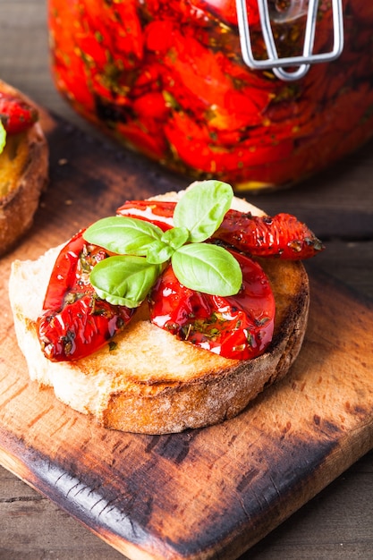 Bruschetta con tomates secos, hojas de albahaca y ajo