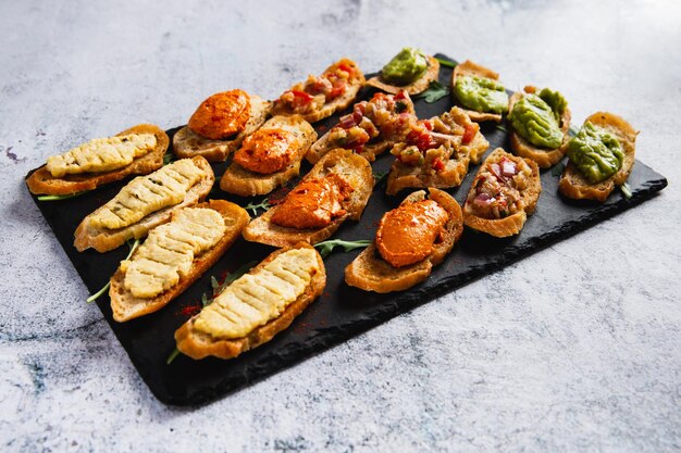 Foto bruschetta variada con varios ingredientes en un plato oscuro sobre fondo blanco bruschetta apetitosa