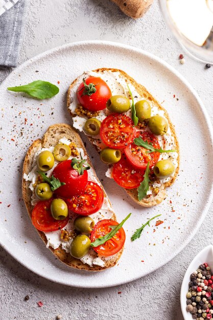 Foto bruschettas con aceitunas y tomates frescos y copa de vino