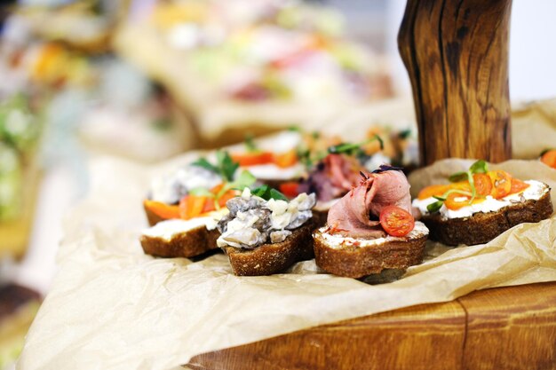 Bruschettas con carne pescado champiñones y queso parmesano en pan Aperitivos fríos Cocina italiana En placa de madera