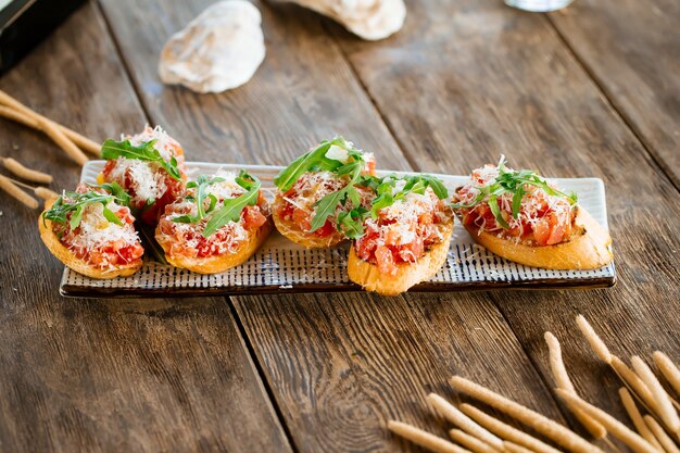 Bruschettas de salmão com queijo ralado e rúcula