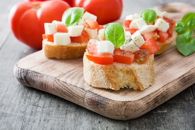 Bruschettas de ensalada Caprese en mesa de madera