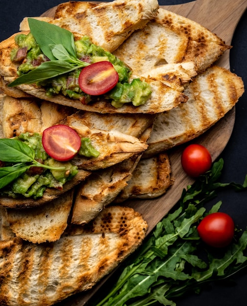 Bruschettas French Toasts mit Guacamole-Basilikum und Cherry-Tomaten auf Holzbrett mexikanische Snack-Ameise