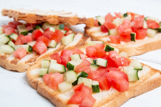 Bruschettas italianas con rodajas de tomate, pepino y verduras. Pan tostado vegetariano con pepino fresco y tomate.