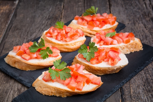 Bruschettas italianas tradicionais com tomate cereja na placa de pedra