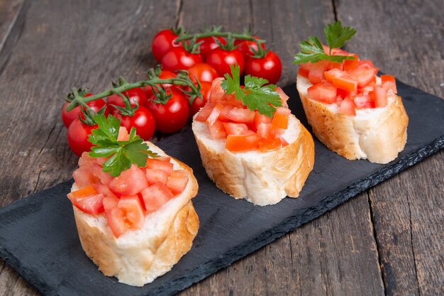 Bruschettas italianas tradicionales con tomates cherry en placa de piedra