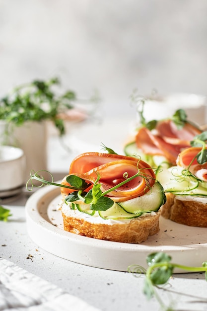 Bruschettas mit Baguette-Speck-Frischkäse-Mikrogemüse, frischer Gurke und Sprossen in Zusammensetzung